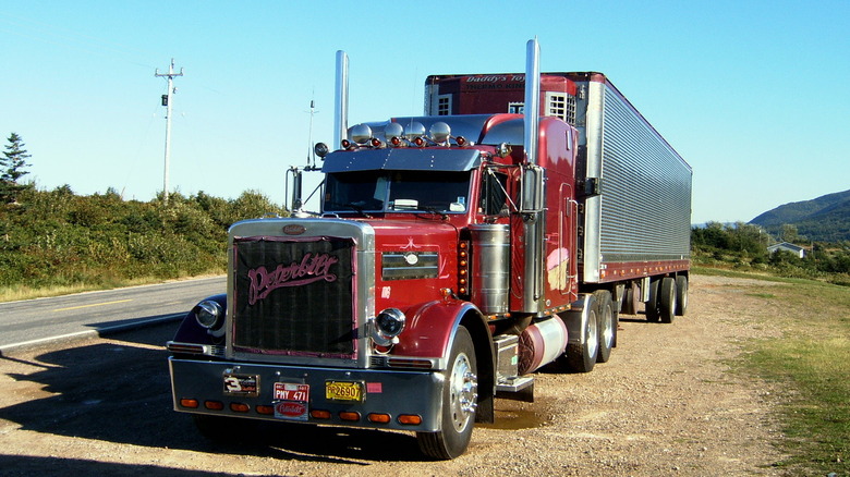 Peterbilt 359 with box trailer parked on dirt next to a two-lane road.