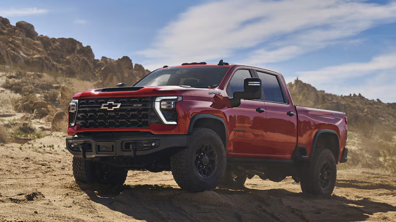 A red 2025 Chevrolet Silverado Heavy Duty pickup truck photographed on rough terrain