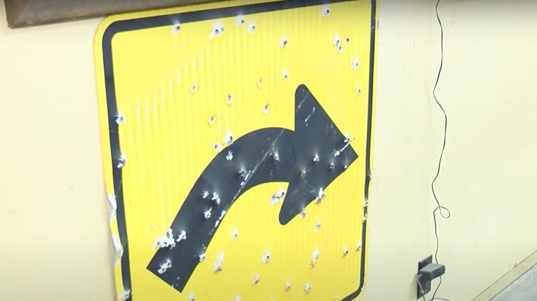 Yellow road sign riddled with bullet holes