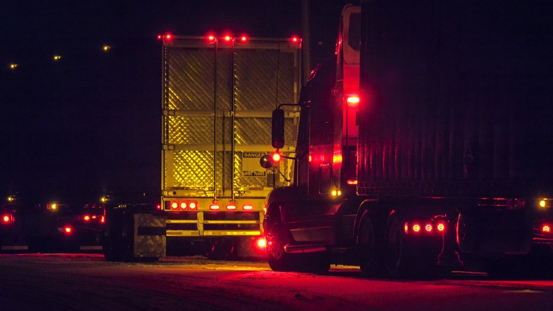 Two brightly illuminated semi-truck tractor trailer trucks