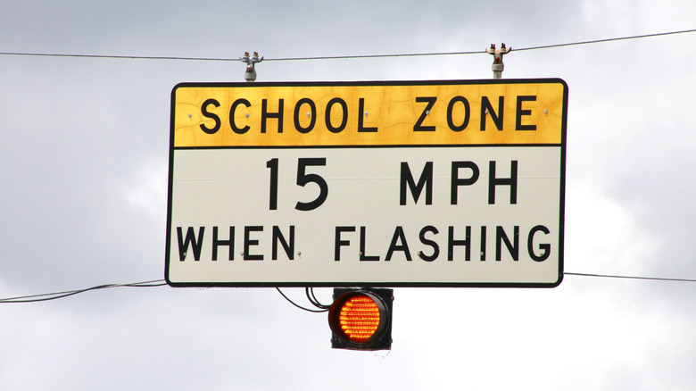 A speed limit sign with a flashing yellow light due to a school zone