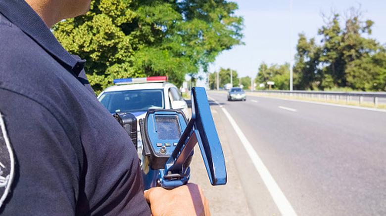 cop using speed radar on side of road