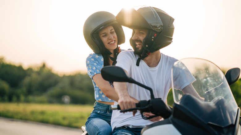 Young couple riding on a motorcycle and wearing helmets