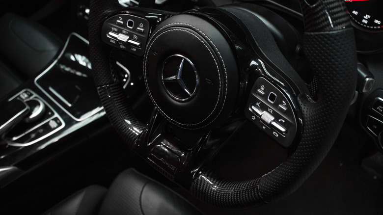 A close up shot of an aftermarket flat bottom carbon fibre steering Mercedes AMG steering wheel.
