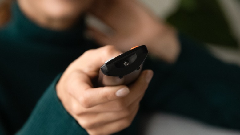 TV remote in a woman's hand pointed at the camera