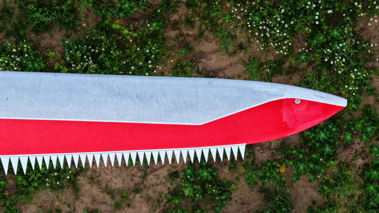 A serrated edge on a red and silver wind turbine blade