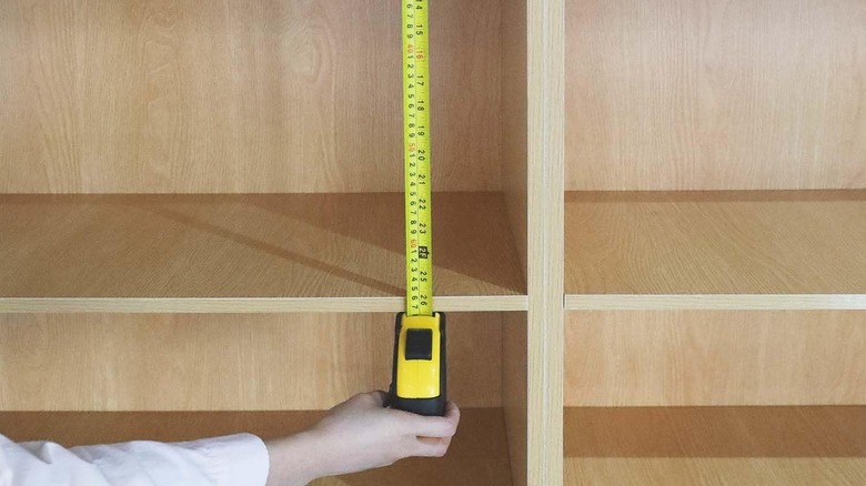 person measuring outside of shelf