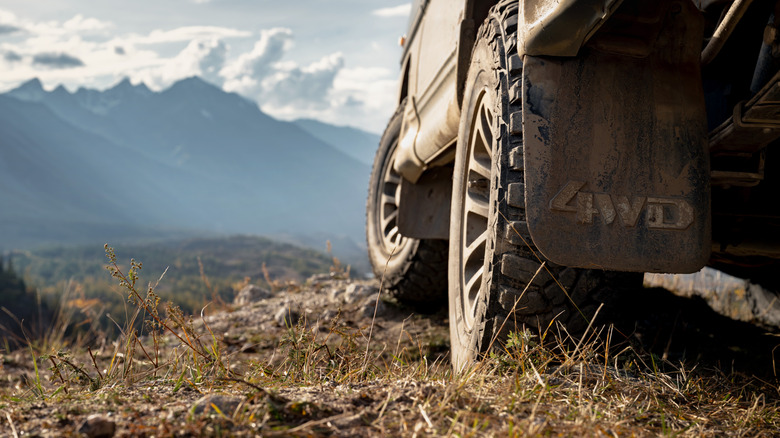 Rear shot of a 4WD truck's dirty off-roading tire while parked on top of a mountain