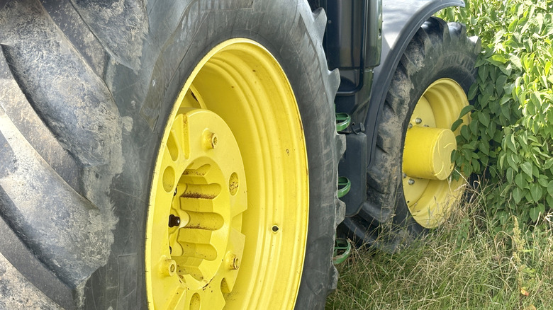 A close-up of a large rear tractor tire with a distinctive yellow hub and black tread.
