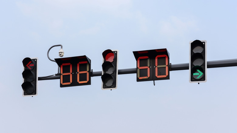 Horizontal traffic lights against a cloudy sky with countdown timers between them.