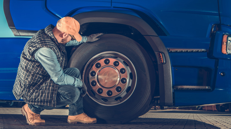 Semi truck driver checking tire