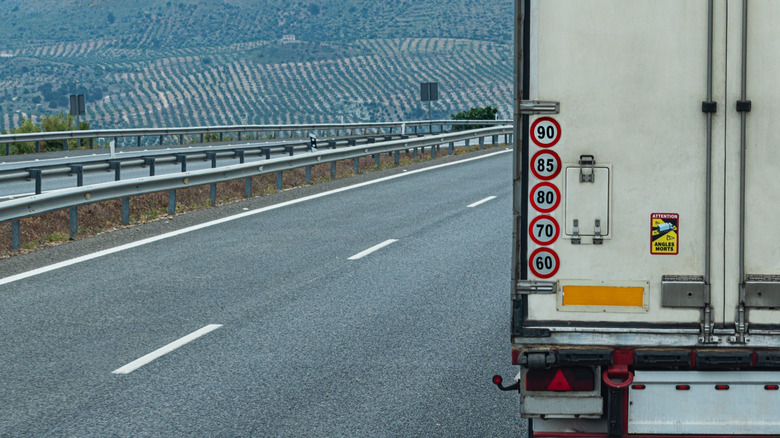 Close-up of multiple speed limit stickers on the rear of a truck.