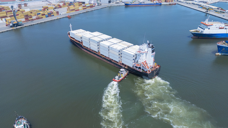 tugboat nudging cargo ship in harbor