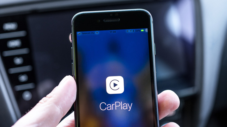 An old iPhone showing the CarPlay logo inside a car.