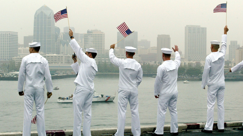 U.S. sailors wave while manning the rails after returning home from a tour.