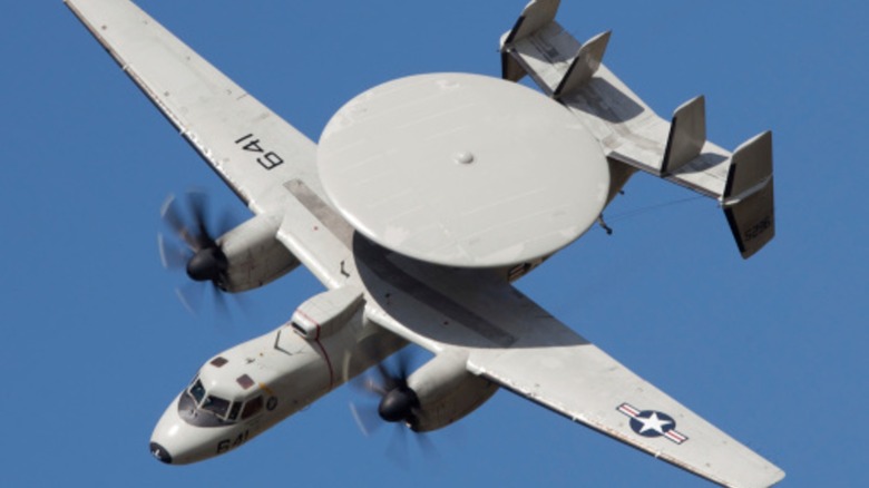 An E-2 Hawkeye flying with a clear blue sky in the background