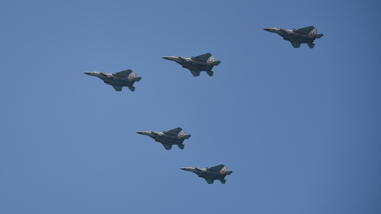 Five F-22 Raptors against a blue sky.