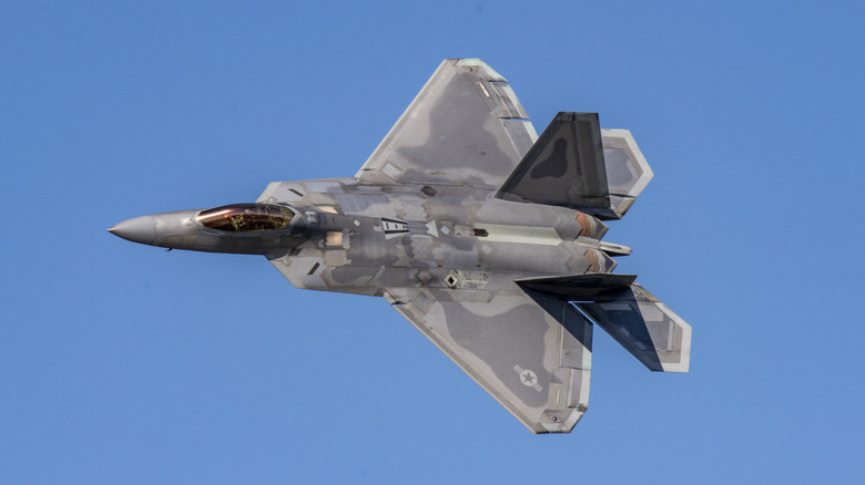 An F-22 Raptor flying against a blue sky.