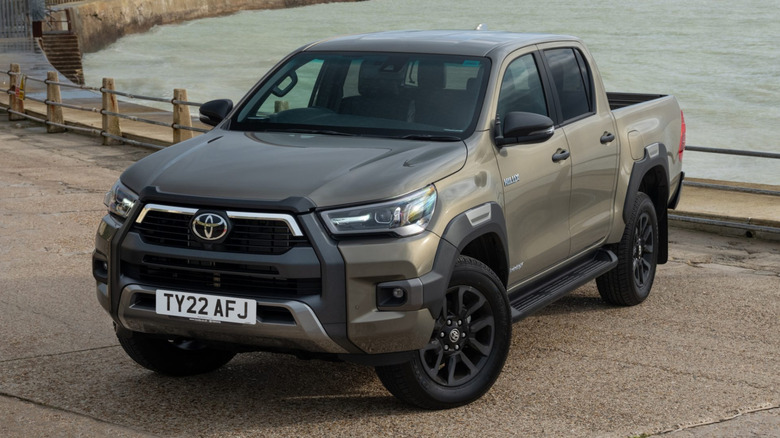 A bronze Toyota Hilux diesel pickup parked by a quay