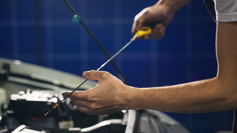 Man taking out dipstick and checking oil levels