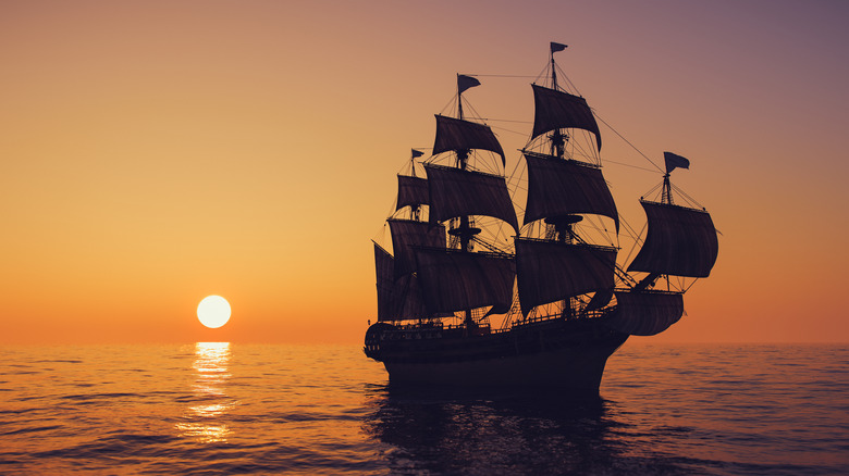 Old schooner at sail with sun setting in background