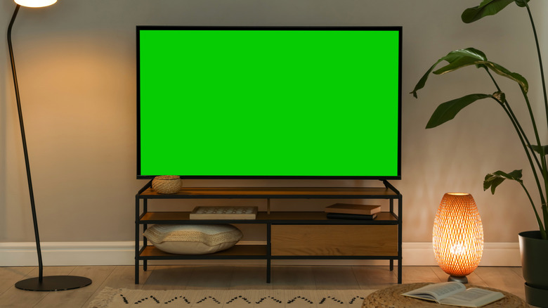A large TV with legs that sit right near the edge of the console