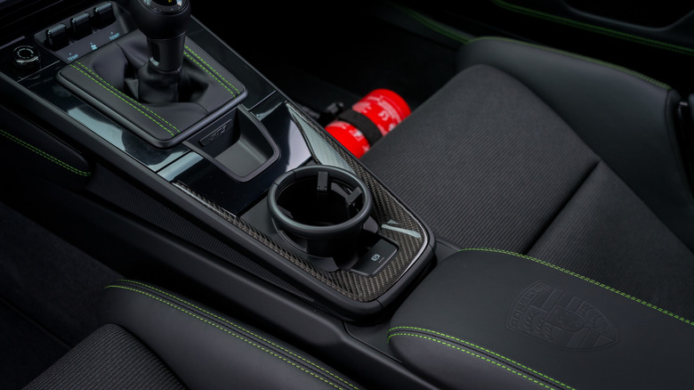 The central cup holder on a Porsche 911 GT3, green stitching and carbon fiber trim, Porsche crest on center console