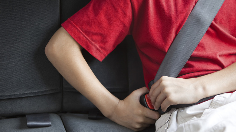 A kid fastening his seat belt