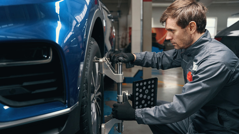man doing wheel alignment at shop