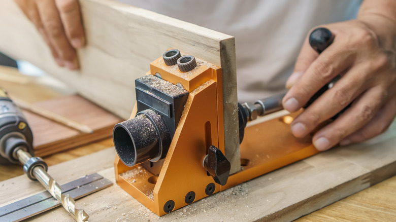 Carpenter attaching pocket hold jig to board