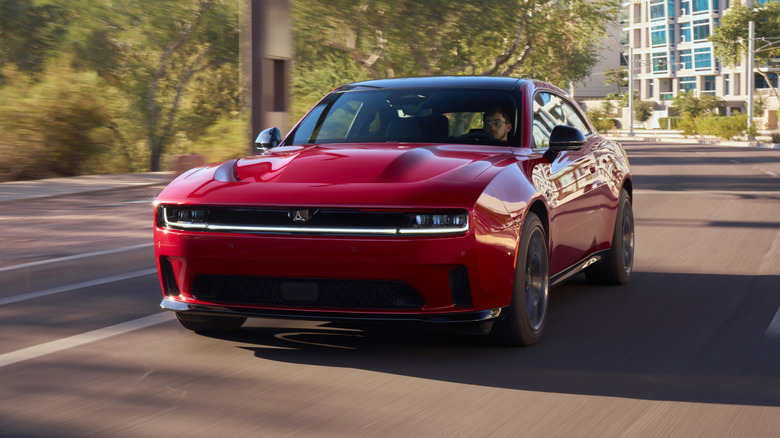A red Dodge Charger Daytona Scat Pack driving on an urban road, front 3/4 view
