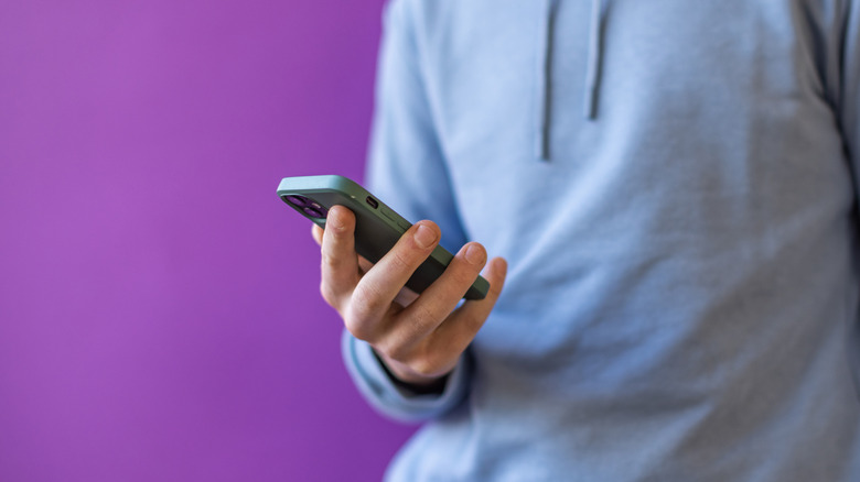 person holding iphone purple background