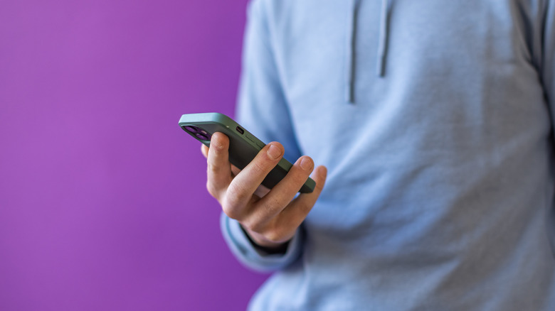 person holding iphone purple background