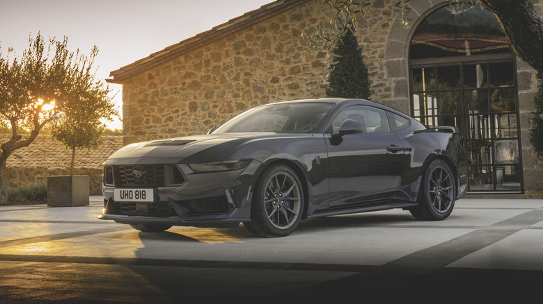 Front 3/4 view of a Ford Mustang Dark Horse parked outside of a house at sunset
