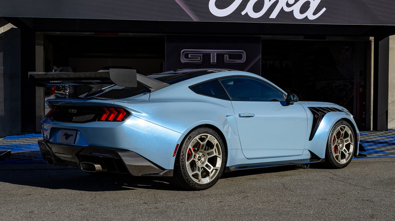 Rear 3/4 view of blue Ford Mustang GTD parked in front of garage.