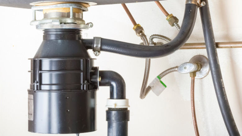 A view of a garbage disposal unit from under the sink.
