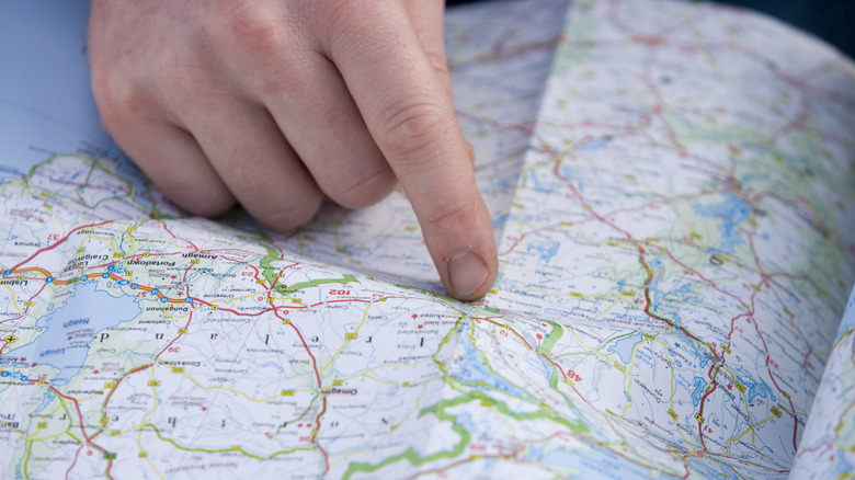 A person pointing to area on a paper map