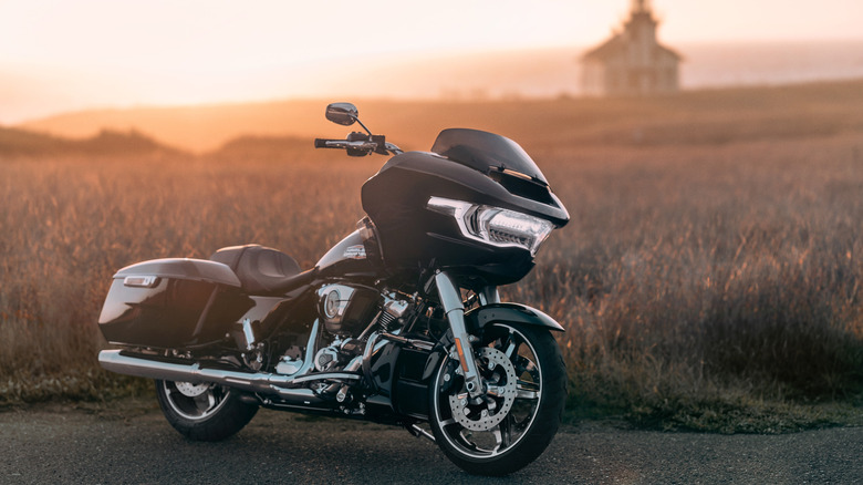 A black Road Glide parked on the side of the road at sunset with a blurred church behind it