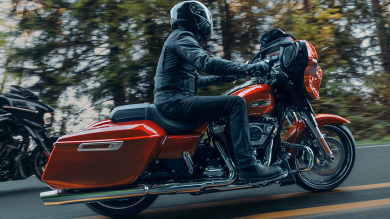 A biker rides a red Street Glide up a forest road