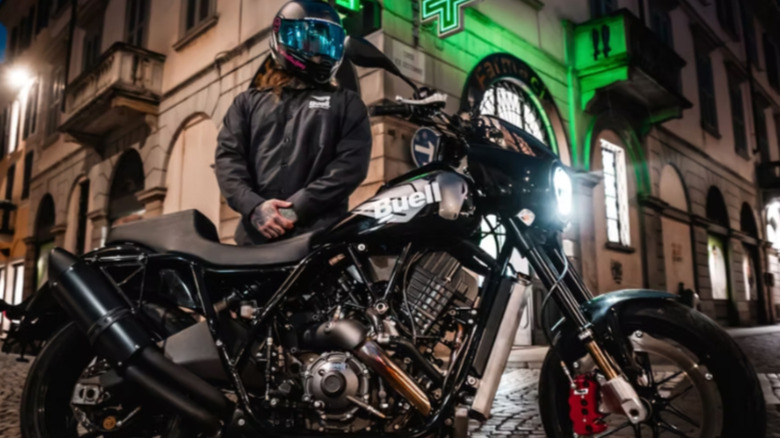 A biker standing alongside black Buell bike