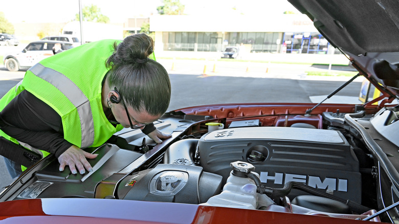A person in a high-vis jacket locking into a HEMI engine bay.