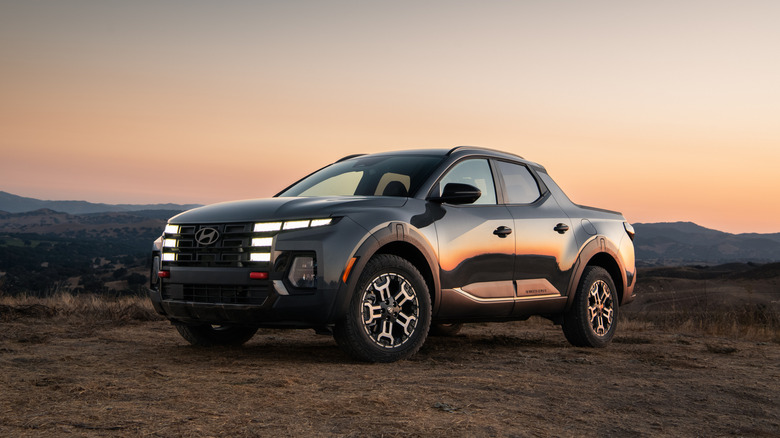 The Hyundai Santa Cruz XRT parked on a dirt area against a sunset, front 3/4 view