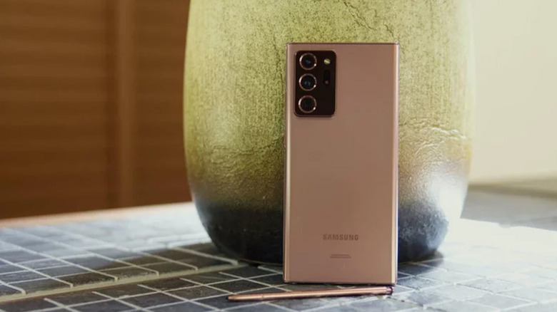 A pink Samsung Galaxy Note 20 Ultra against a vase on a table