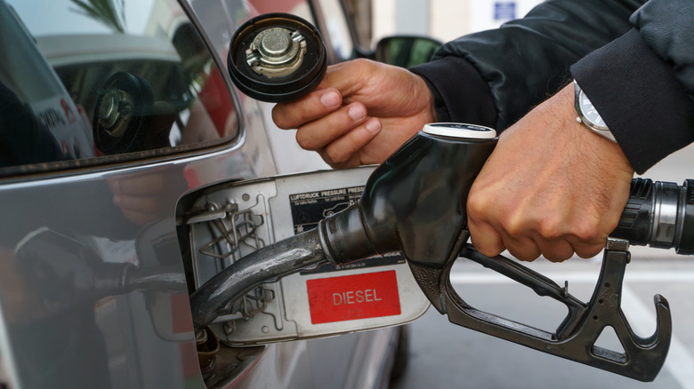 Hand fills up vehicle with diesel fuel