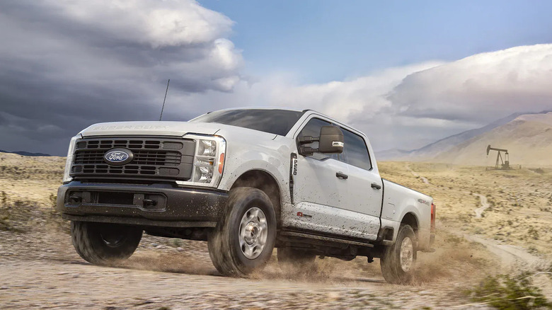 2027 Ford F-250 Super Duty driving through desert terrain, front-left 3/4 view