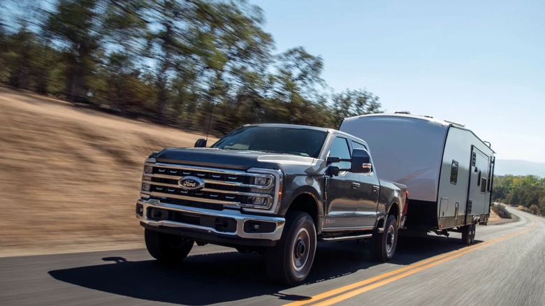 2023 Ford Super Duty towing trailer on road, front-left 3/4 view