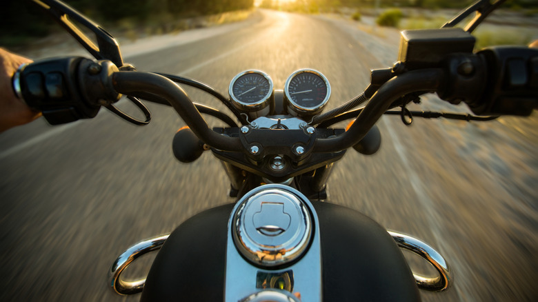 Close up of handlebars and dials of motorcycle on the road.