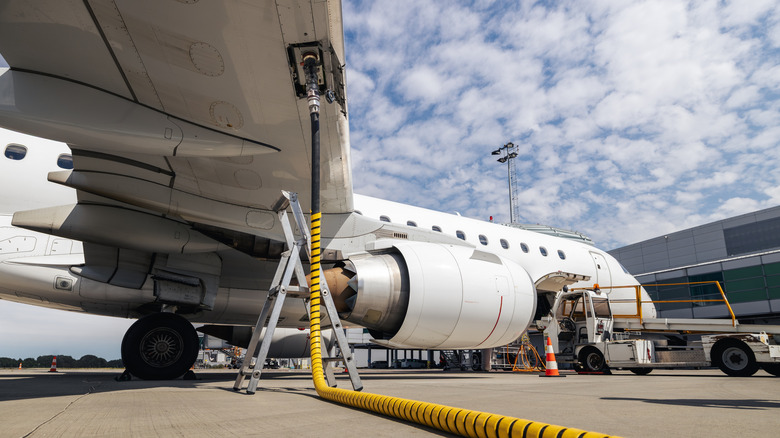 Underwing view of a plane refueling at gate
