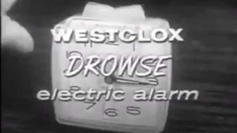 Still from a 1961 commercial for the Westclox Drowse electric alarm. It shows a black and white image of an analog alarm clock with a large two-sided button on top. In front are the words "WESTCLOX DROWSE electric alarm"