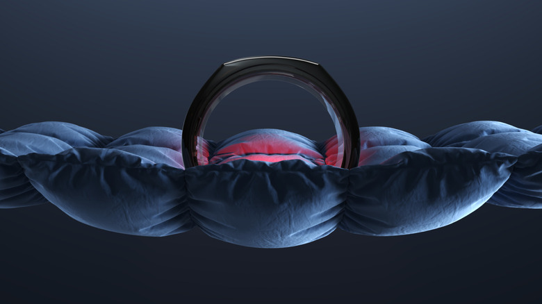 A red glowing Oura Ring placed on a twisted cloth.